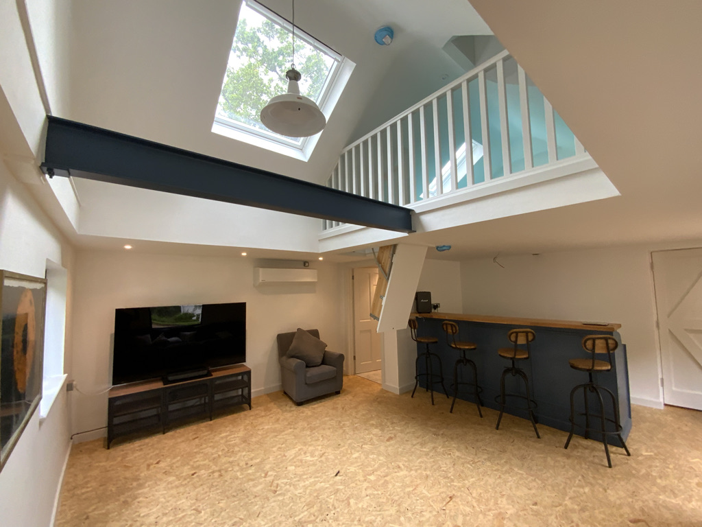Open-plan garden room conversion with steel beam, skylight, mezzanine level and bar seating
