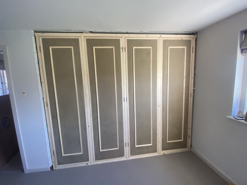 Four-door fitted wardrobe frontage hand-built into an alcove, part-finished before painting