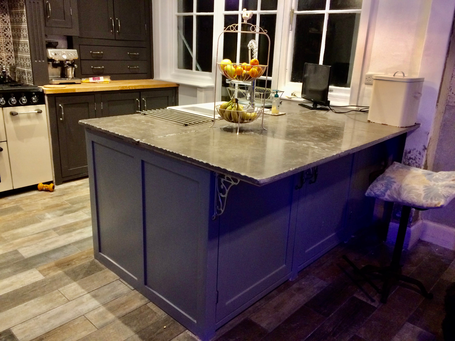 Deep blue painted kitchen island with a thick natural stone worktop and breakfast bar