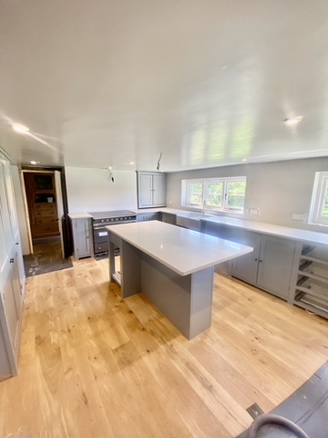 Newly fitted grey kitchen with a central island, quartz worktops and oak flooring