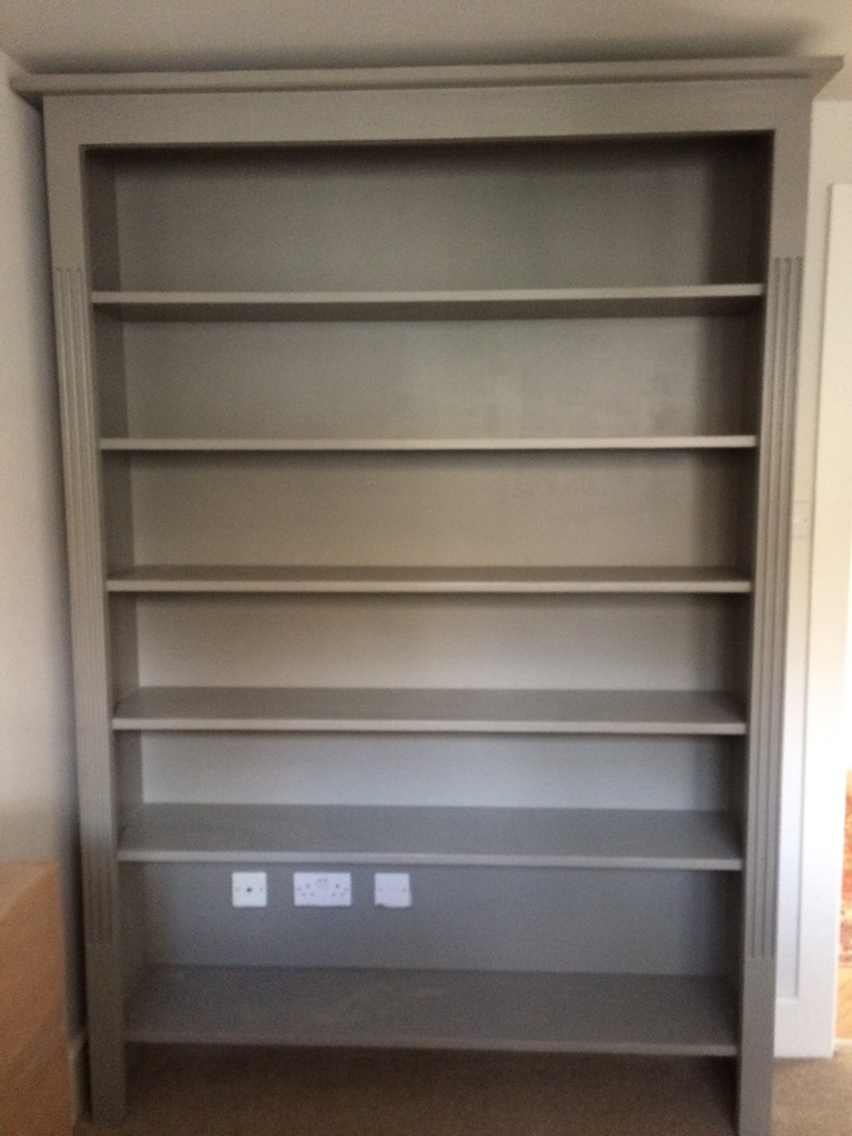 Tall fitted bookcase painted in soft grey with adjustable shelves and a moulded cornice