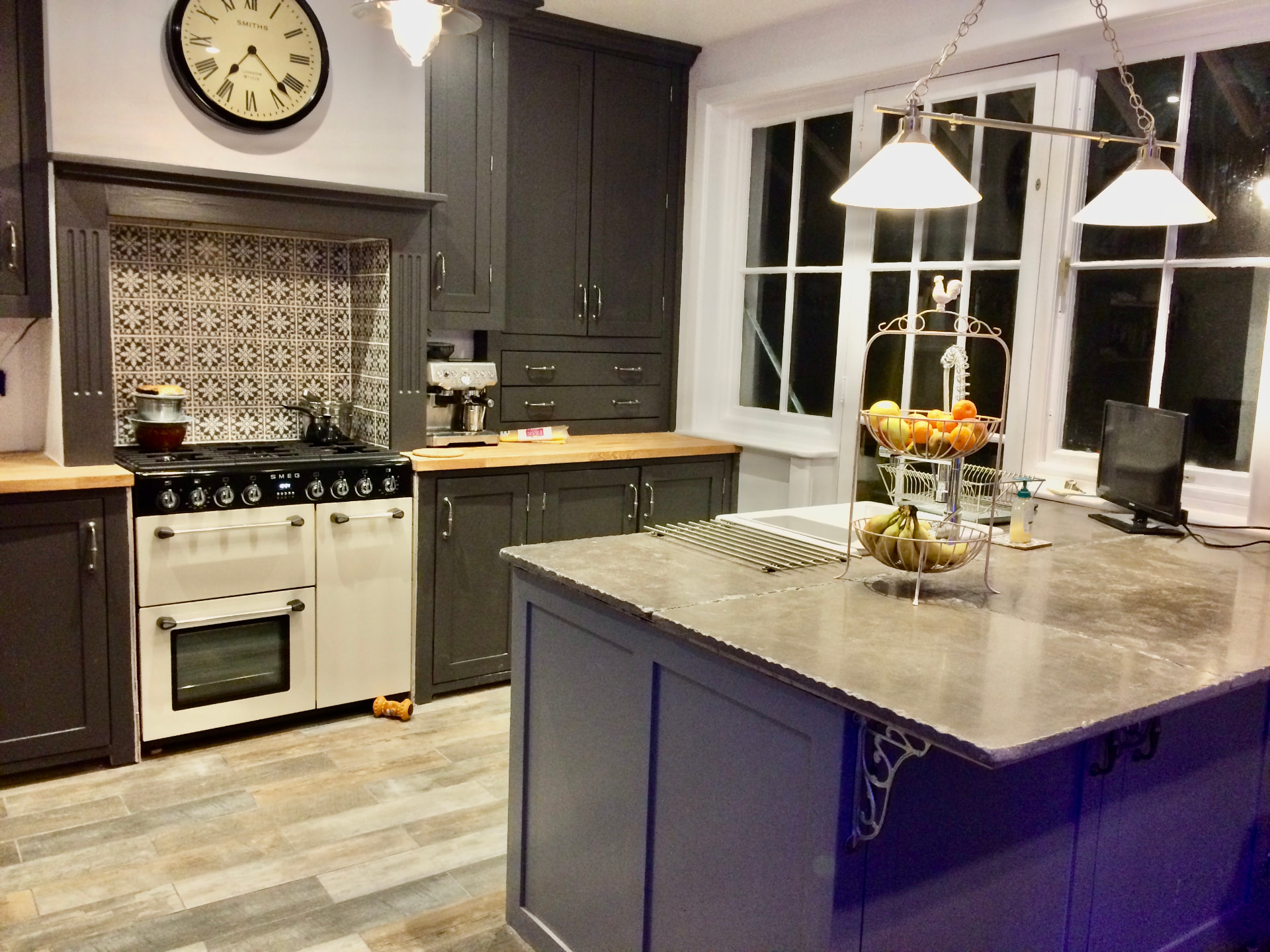 Charcoal-grey shaker kitchen with oak worktops, range cooker, patterned tiled splashback and stone-topped island